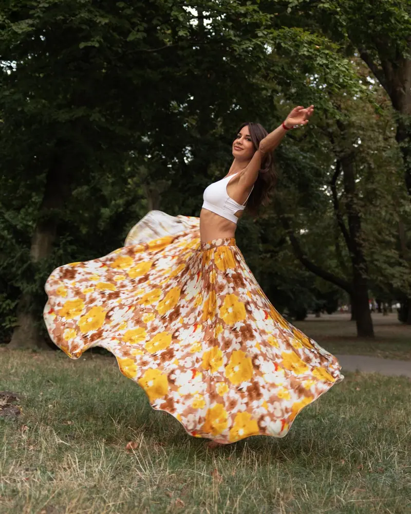 Eniko twirling in a flowing floral skirt in a green park